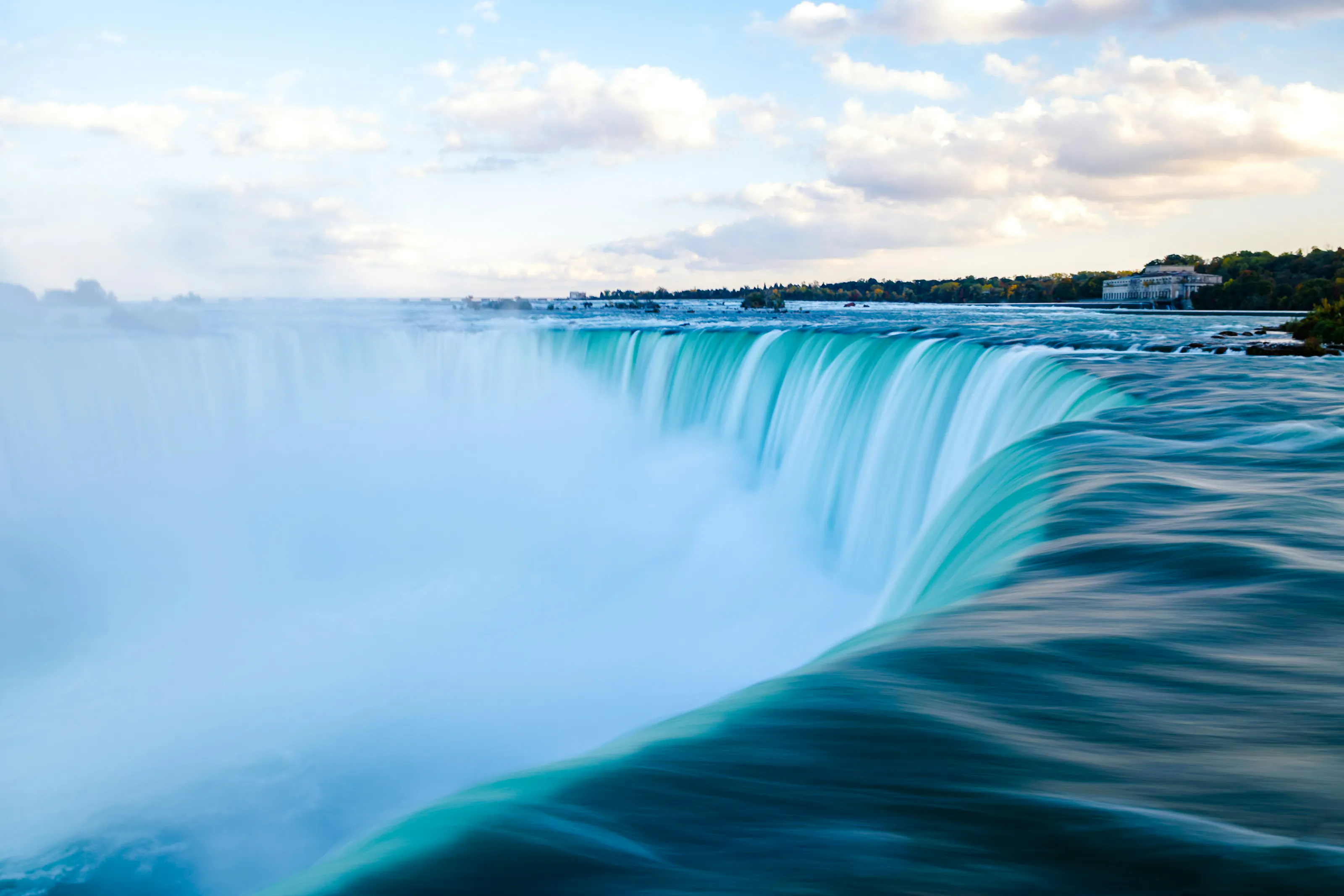 Niagara Falls cascading water viewed from the Canadian side on a clear day.