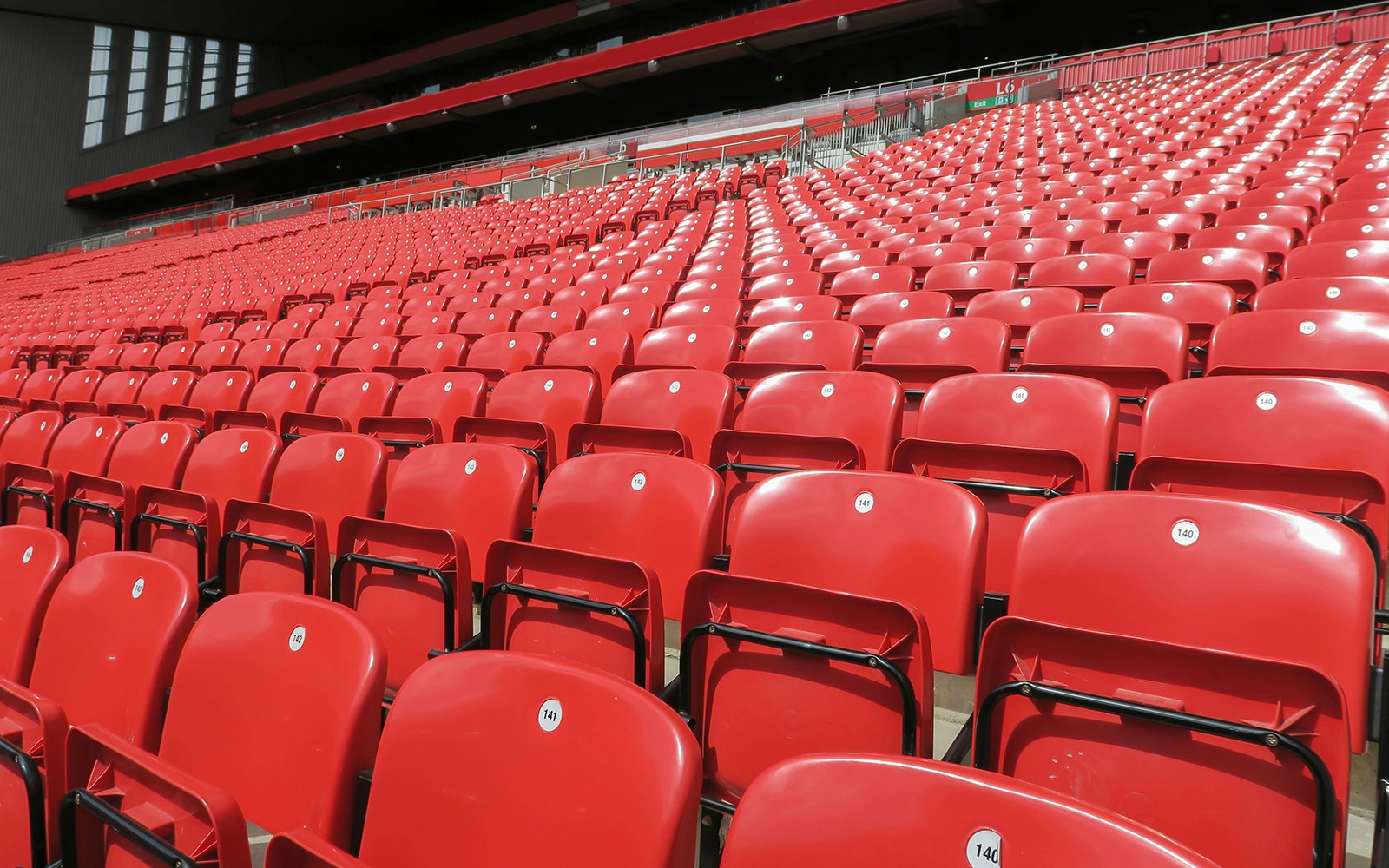 Fileiras de assentos vermelhos em um estádio esportivo.