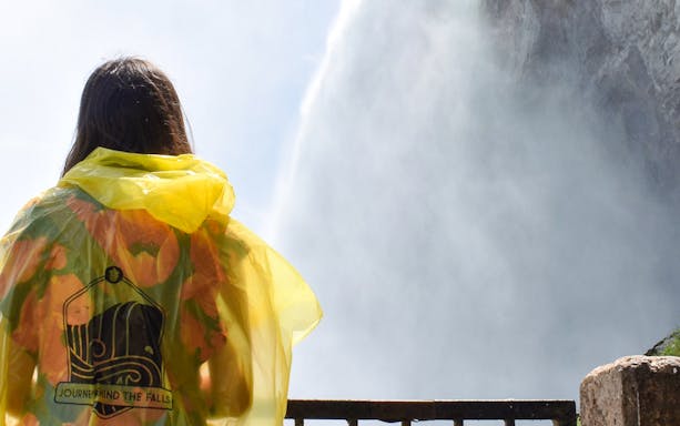 Person in yellow poncho viewing Niagara Falls from behind, Canada.