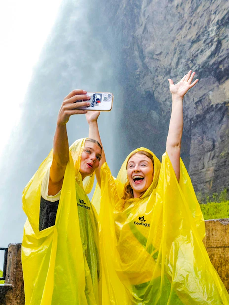 Visitors in yellow ponchos taking a selfie at Journey Behind the Falls, Niagara Falls, Canada.