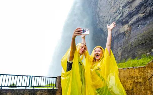 Visitors in yellow ponchos taking a selfie at Journey Behind the Falls, Niagara Falls, Canada.
