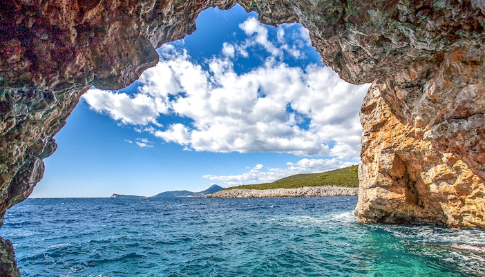 Boat entering Blue Cave on Montenegro coast with clear blue waters.
