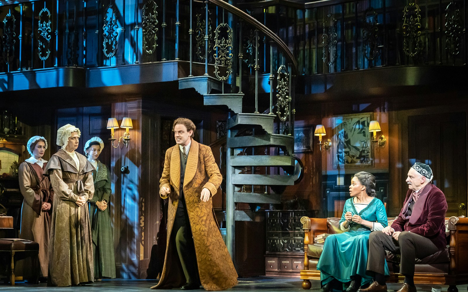 Stage scene from "My Fair Lady" with actors in period costumes and a spiral staircase.