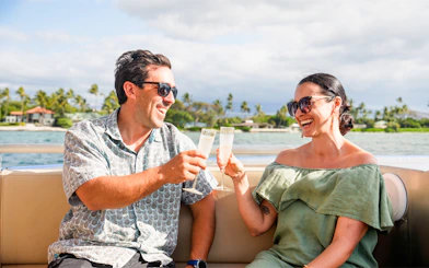 Guests toasting with drinks on a boat along Big Island’s Kohala Coast.