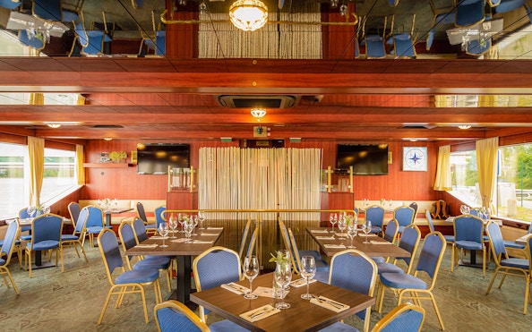 Dining area setup on a Danube river cruise ship with tables and blue chairs.