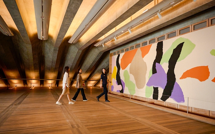 People on a guided tour in the Utzon Room, Sydney Opera House, viewing colorful wall art.