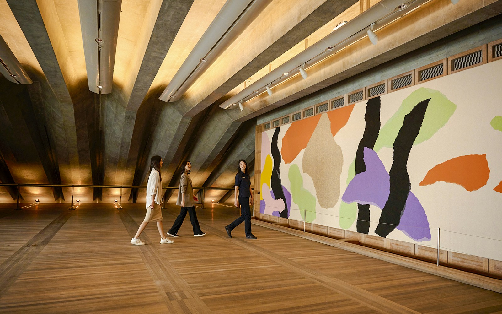 People on a guided tour in the Utzon Room, Sydney Opera House, viewing colorful wall art.