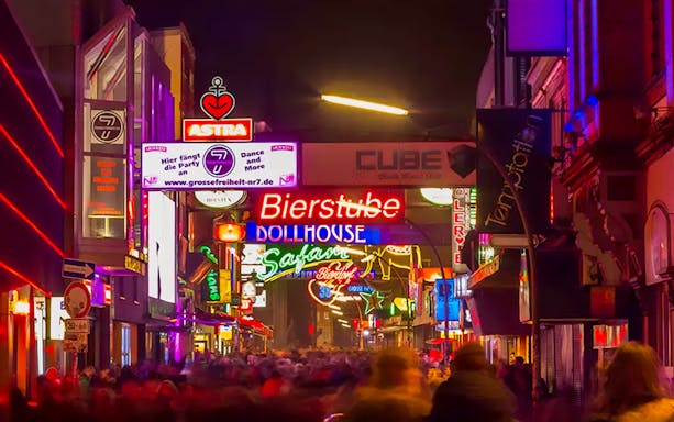 Neon-lit street in St. Pauli, Hamburg, featuring bars and clubs on a guided tour.