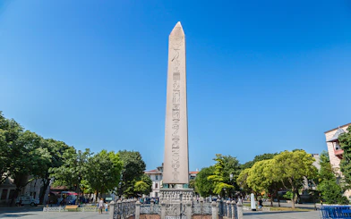 Obelisk of Theodosius in Istanbul's Sultanahmet Square, surrounded by trees and tourists.