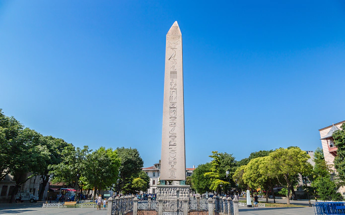 Obelisk of Theodosius in Istanbul's Sultanahmet Square, surrounded by trees and tourists.