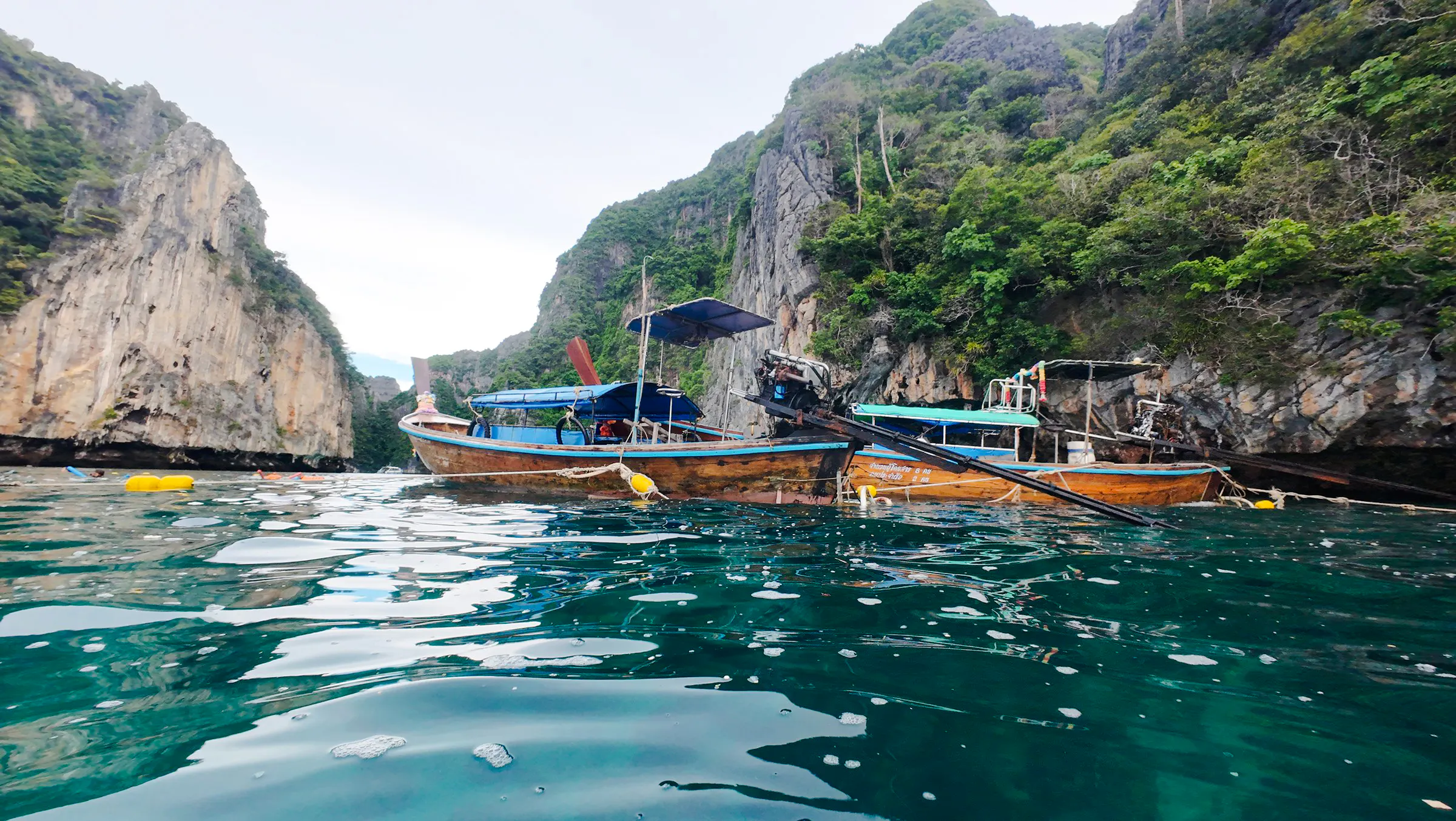 Long-tail boat on turquoise water near limestone cliffs, Koh Phi Phi, Krabi.