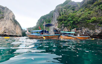 Long-tail boat on turquoise water near limestone cliffs, Koh Phi Phi, Krabi.
