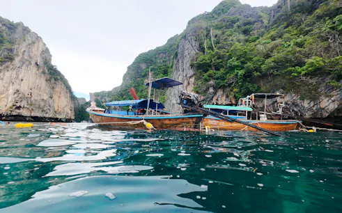 Long-tail boat on turquoise water near limestone cliffs, Koh Phi Phi, Krabi.