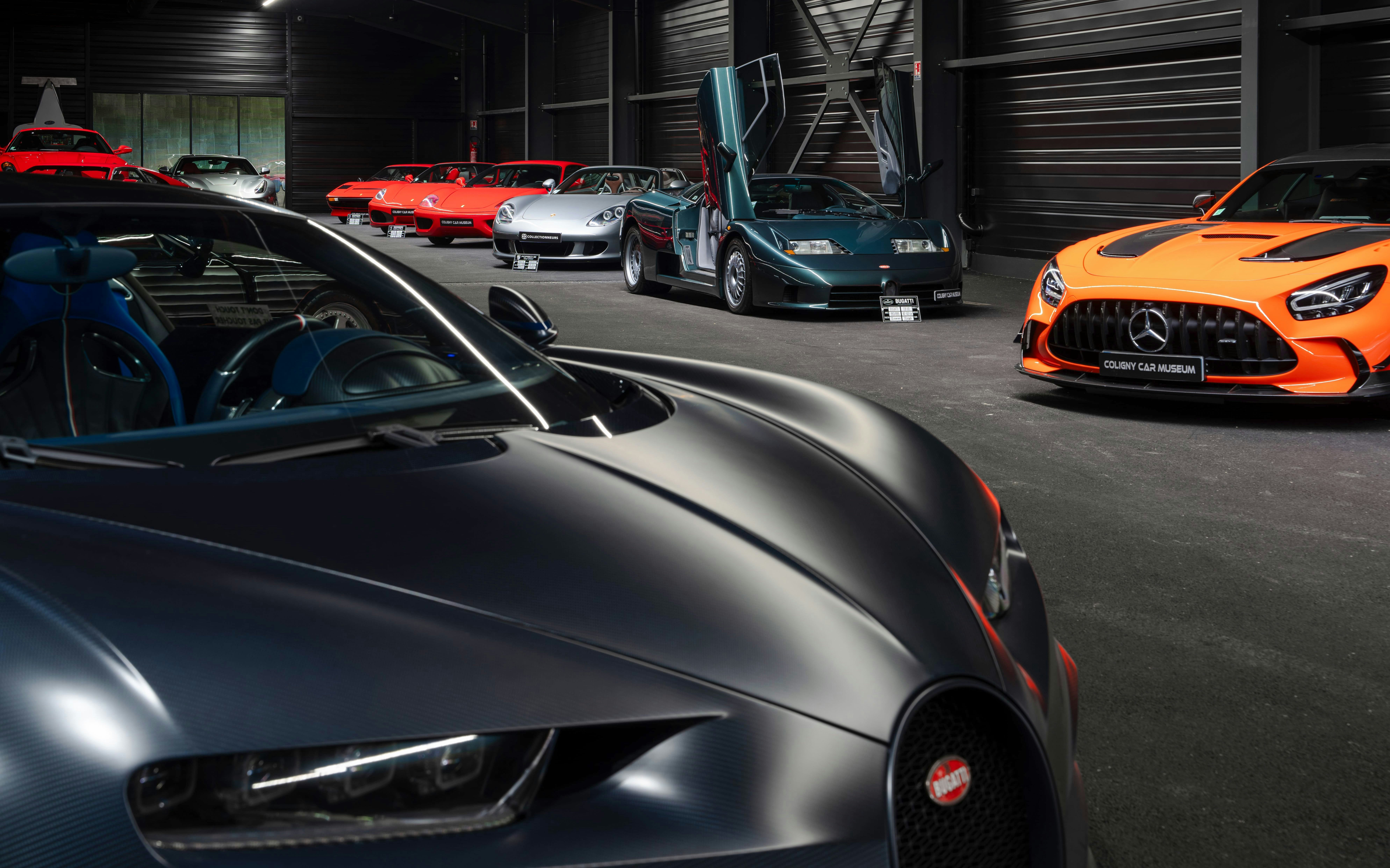 Bugatti EB110 at Coligny Car Museum, Lyon, France, surrounded by luxury cars.