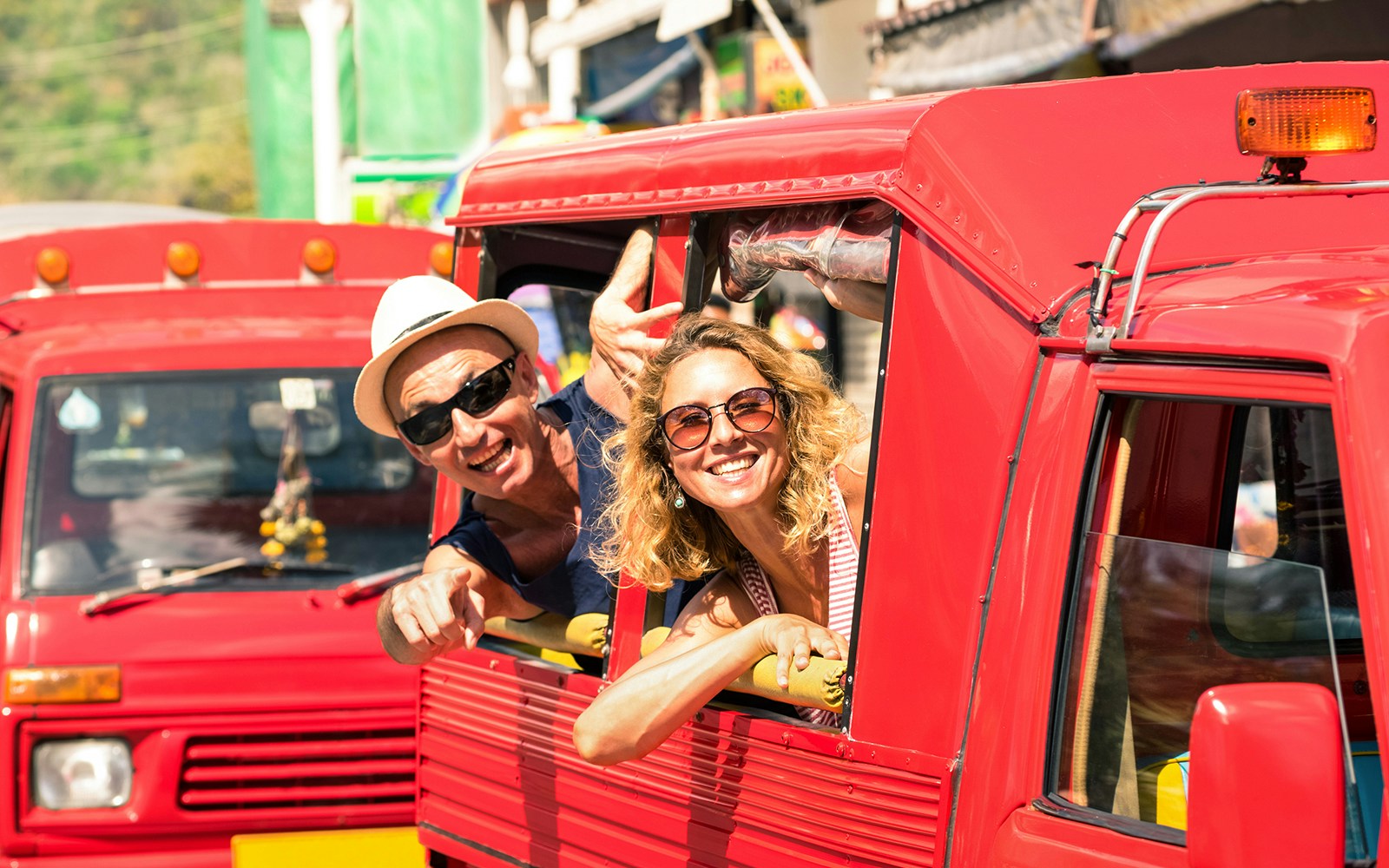 Tourists enjoying a ride in a red taxi in Phuket, Thailand.