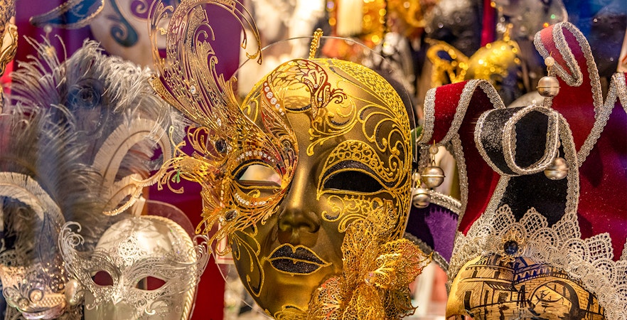 Venice Carnival masks with intricate gold and silver designs on display.