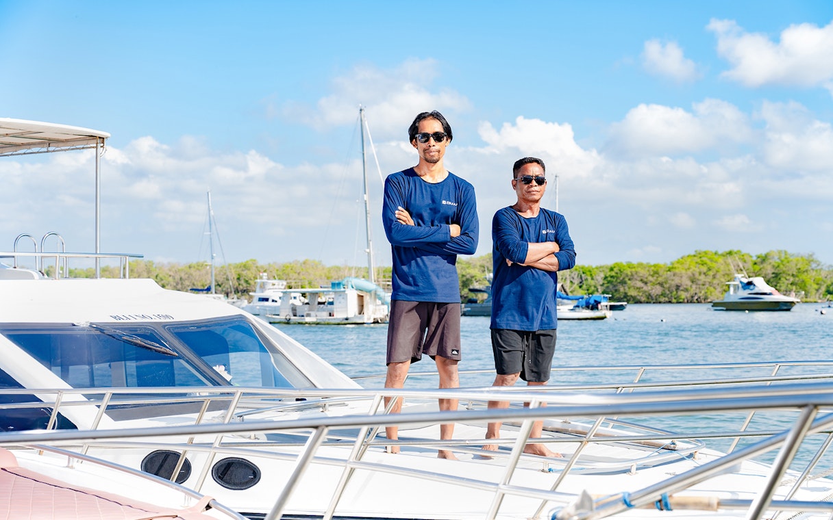 Crew members standing on a boat deck, ready to assist during the trip.