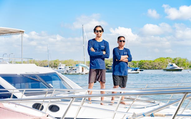 Crew members standing on a boat deck, ready to assist during the trip.