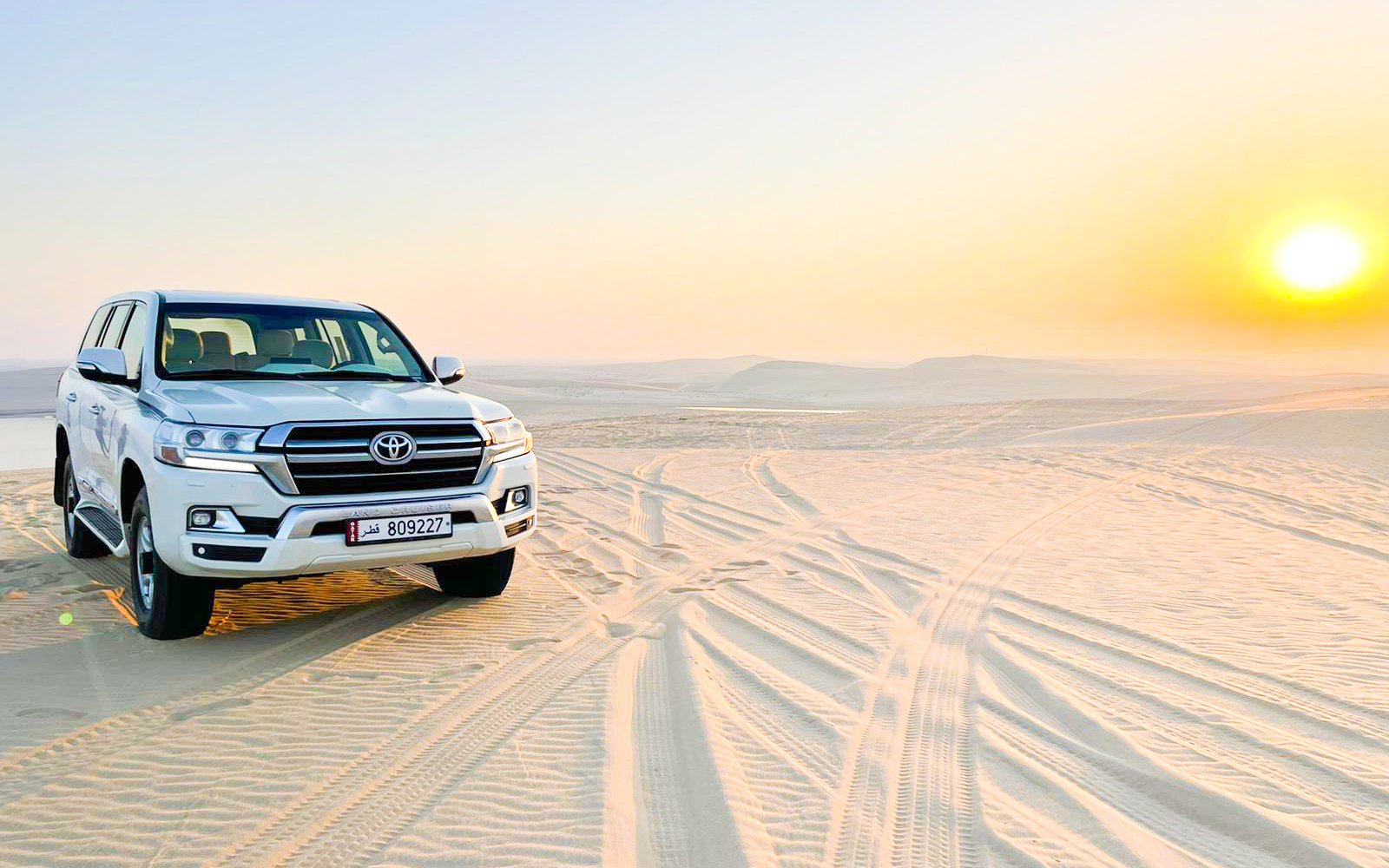 4x4 pickup vehicle on sand dunes at sunrise in Doha desert, Qatar.