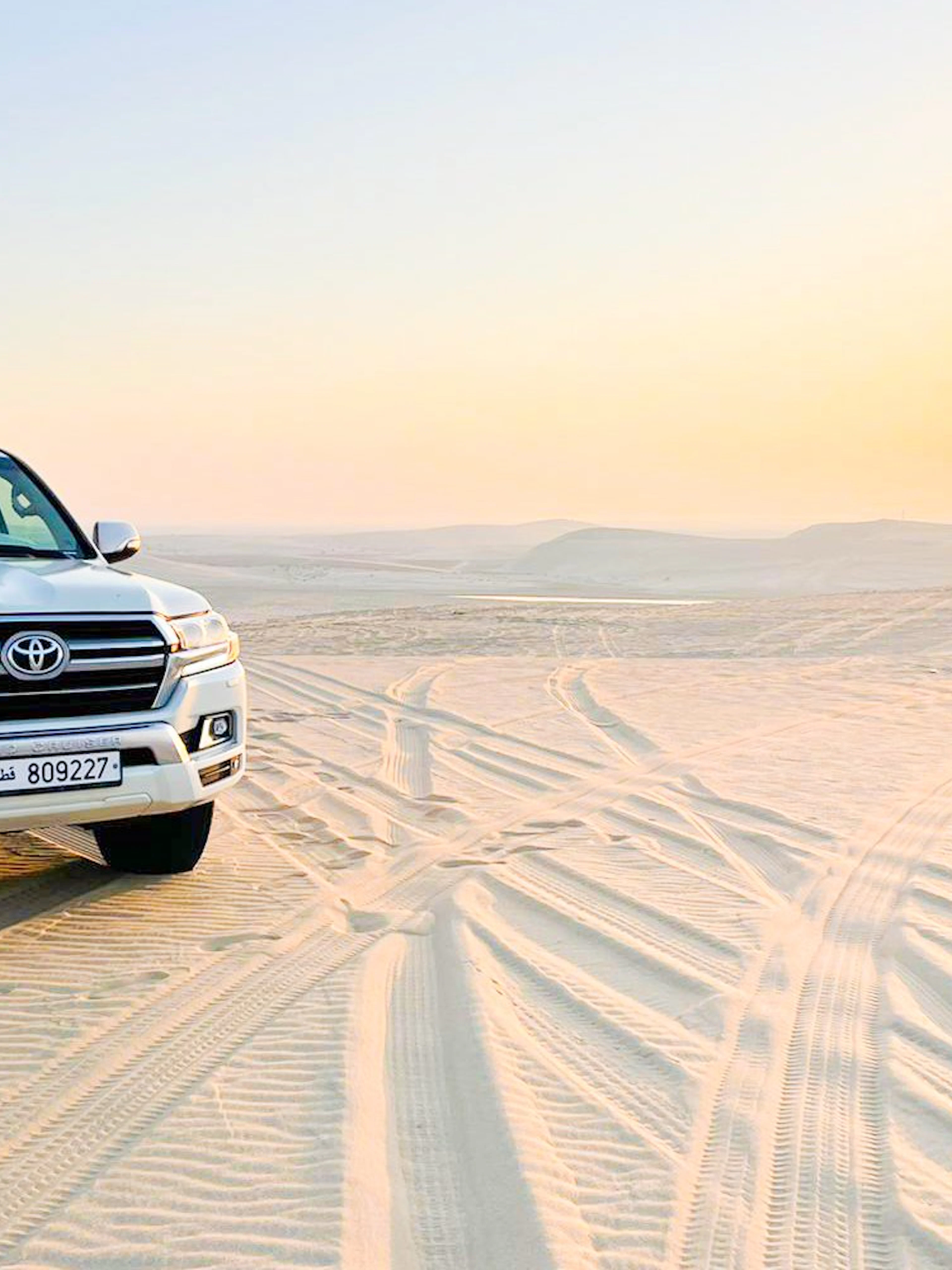 4x4 pickup vehicle on sand dunes at sunrise in Doha desert, Qatar.