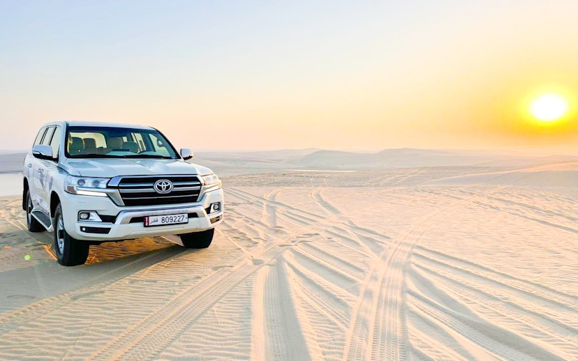 4x4 pickup vehicle on sand dunes at sunrise in Doha desert, Qatar.