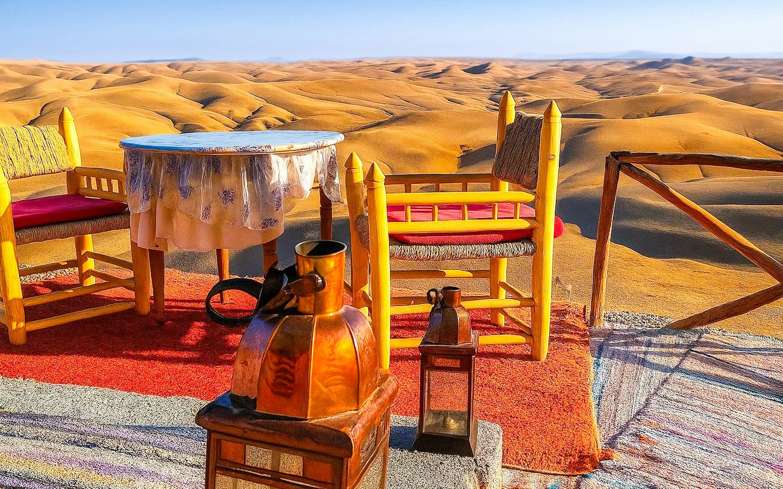 Desert camp setup with chairs and table overlooking Agafay Desert dunes near Marrakech.