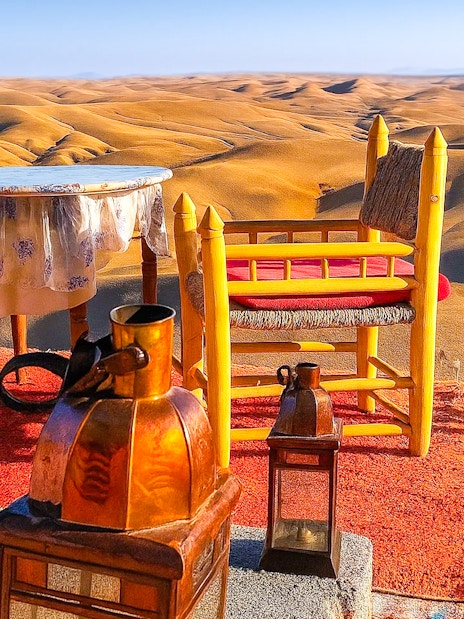 Desert camp setup with chairs and table overlooking Agafay Desert dunes near Marrakech.
