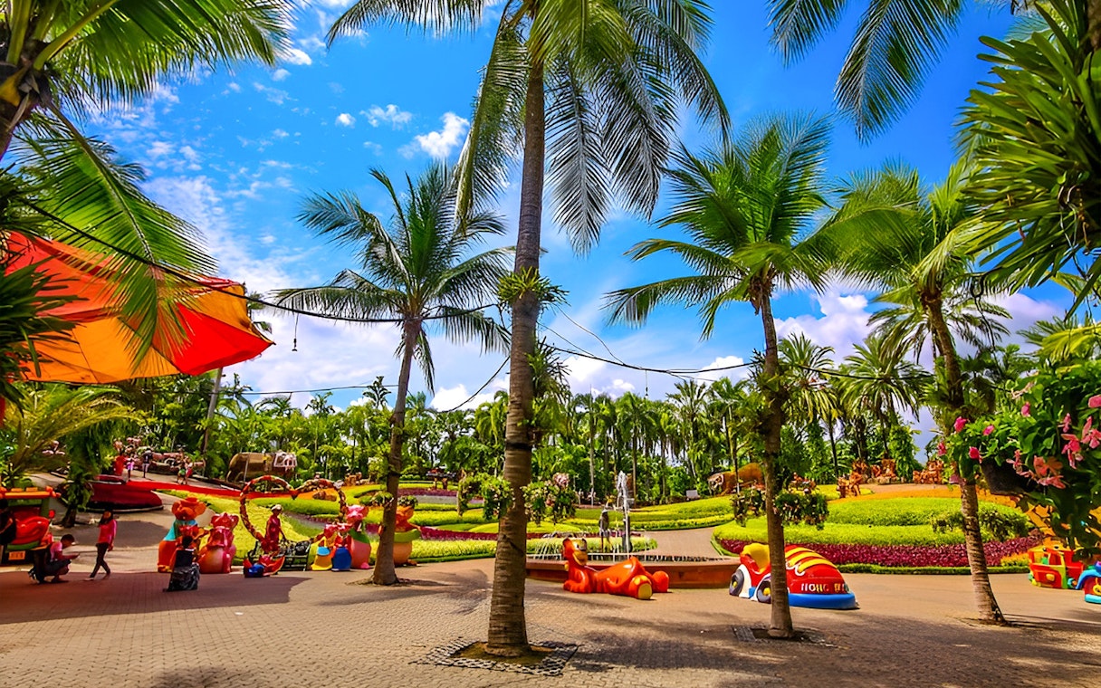 Nong Nooch Tropical Garden with palm trees and colorful sculptures in Pattaya, Thailand.