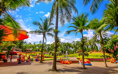 Nong Nooch Tropical Garden with palm trees and colorful sculptures in Pattaya, Thailand.