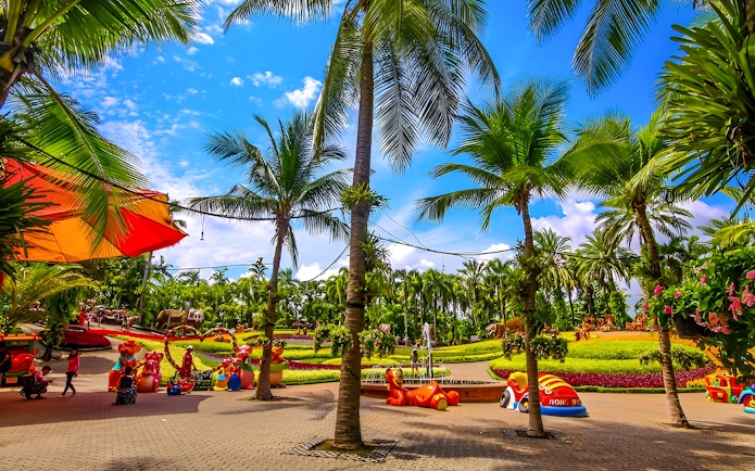 Nong Nooch Tropical Garden with palm trees and colorful sculptures in Pattaya, Thailand.