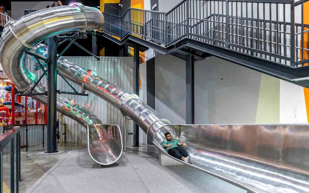Indoor slide at Adrenark Adventure with person sliding down.