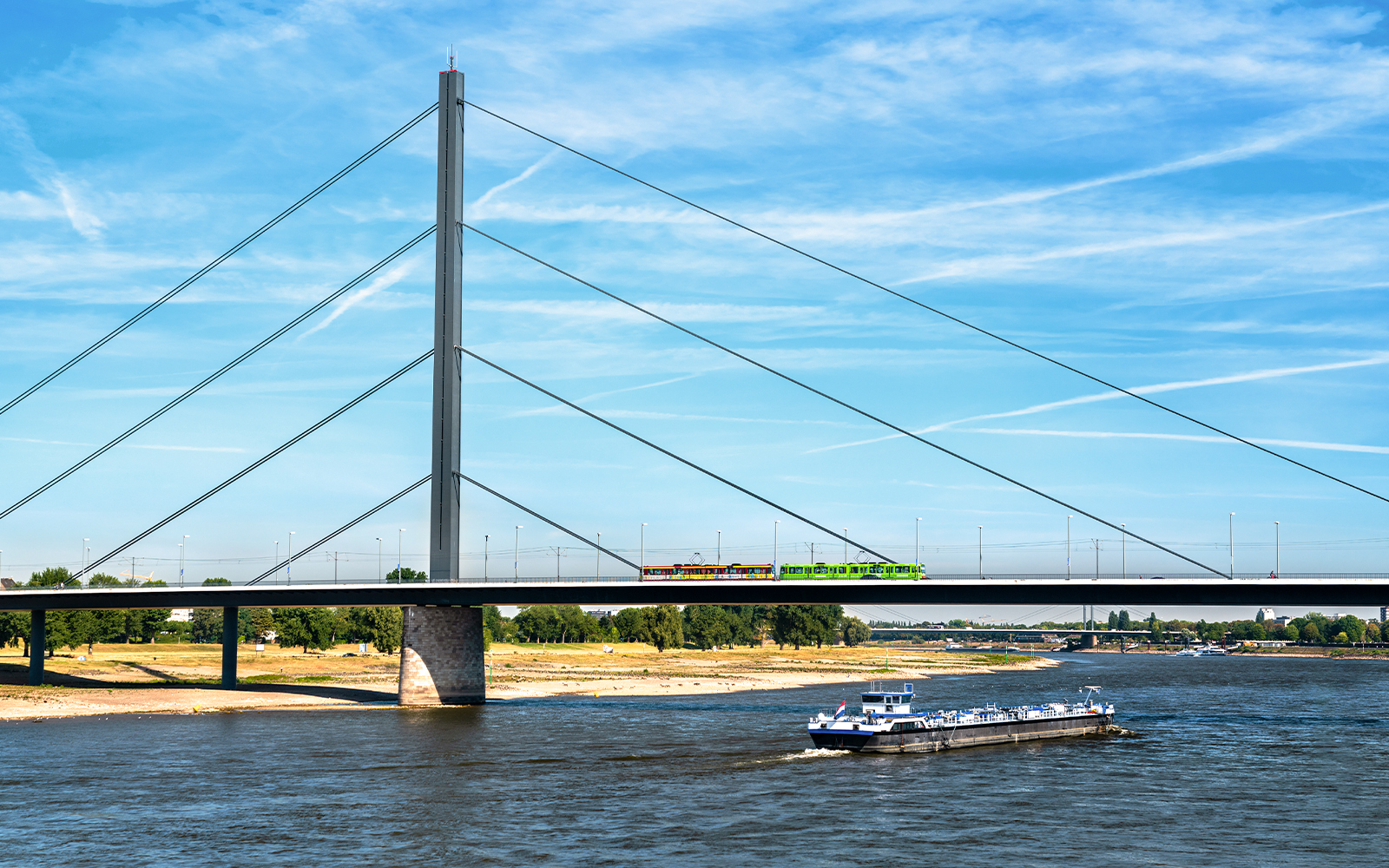 Oberkasseler Bridge in Düsseldorf with tram and boat on the Rhine River.