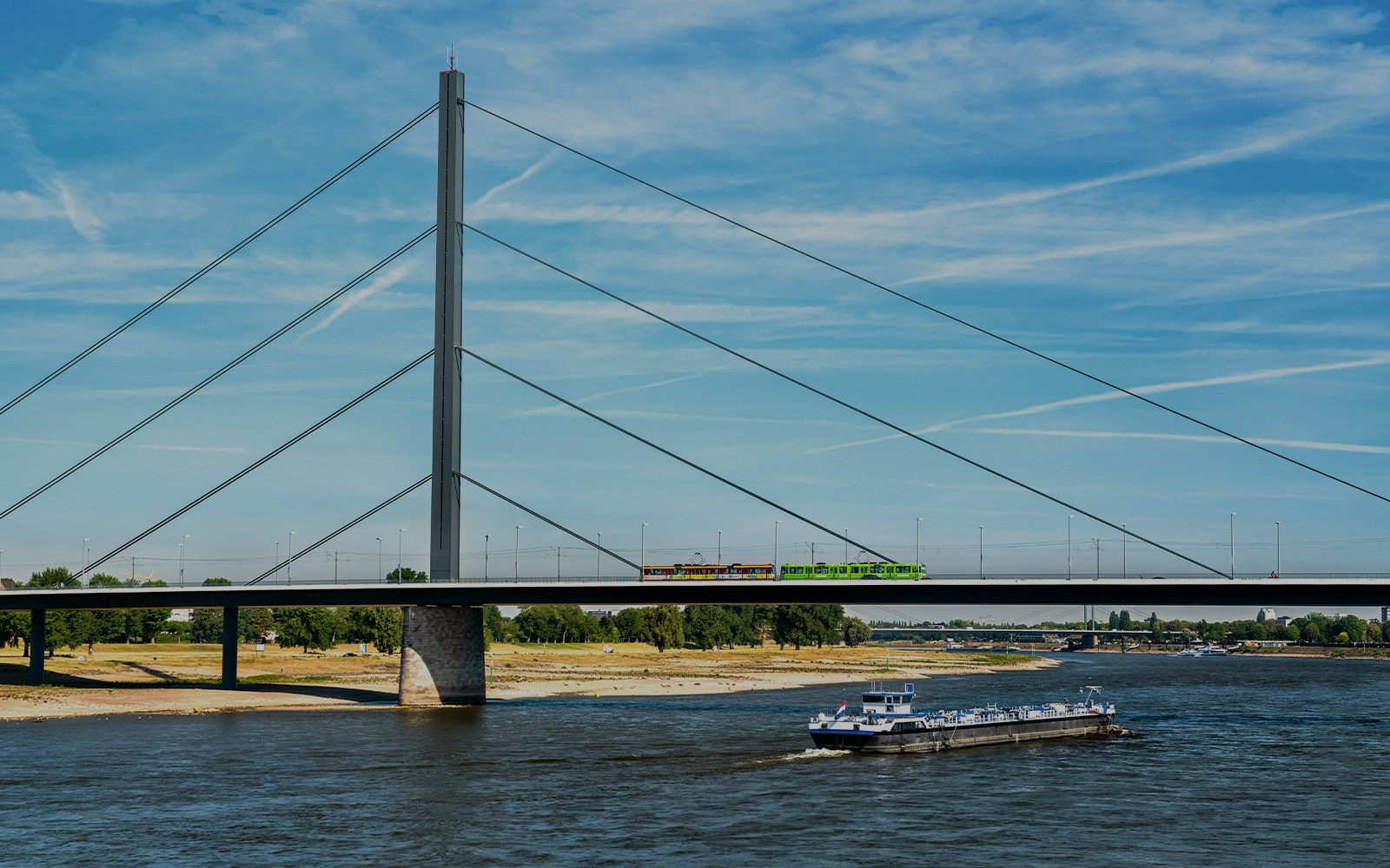 Oberkasseler Bridge in Düsseldorf with tram and boat on the Rhine River.
