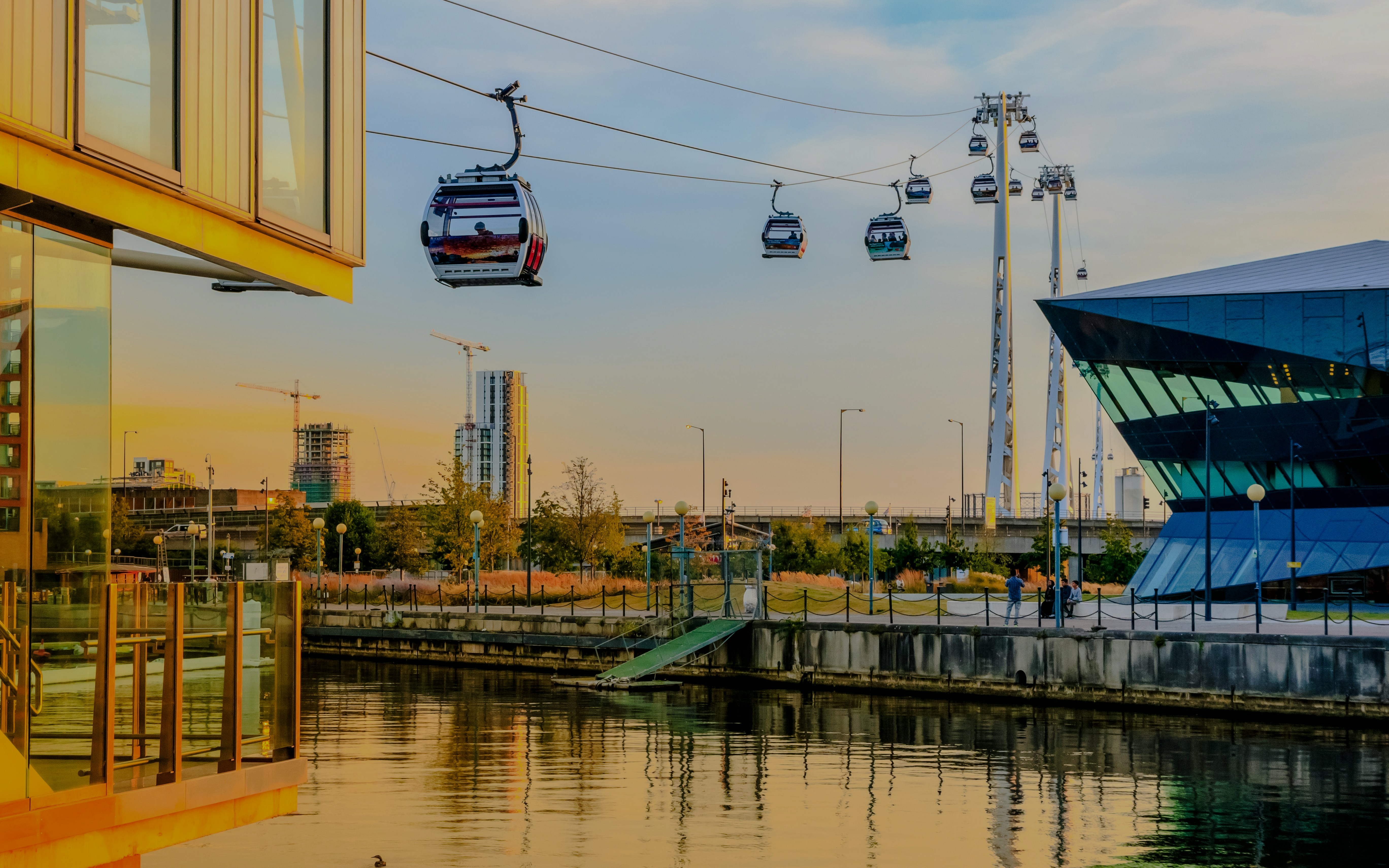 Cable cars over Royal Victoria Dock in London at sunset.