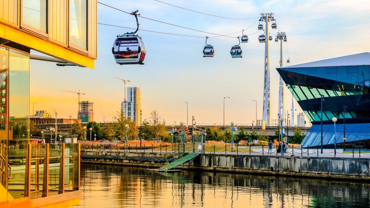 Cable cars over Royal Victoria Dock in London at sunset.