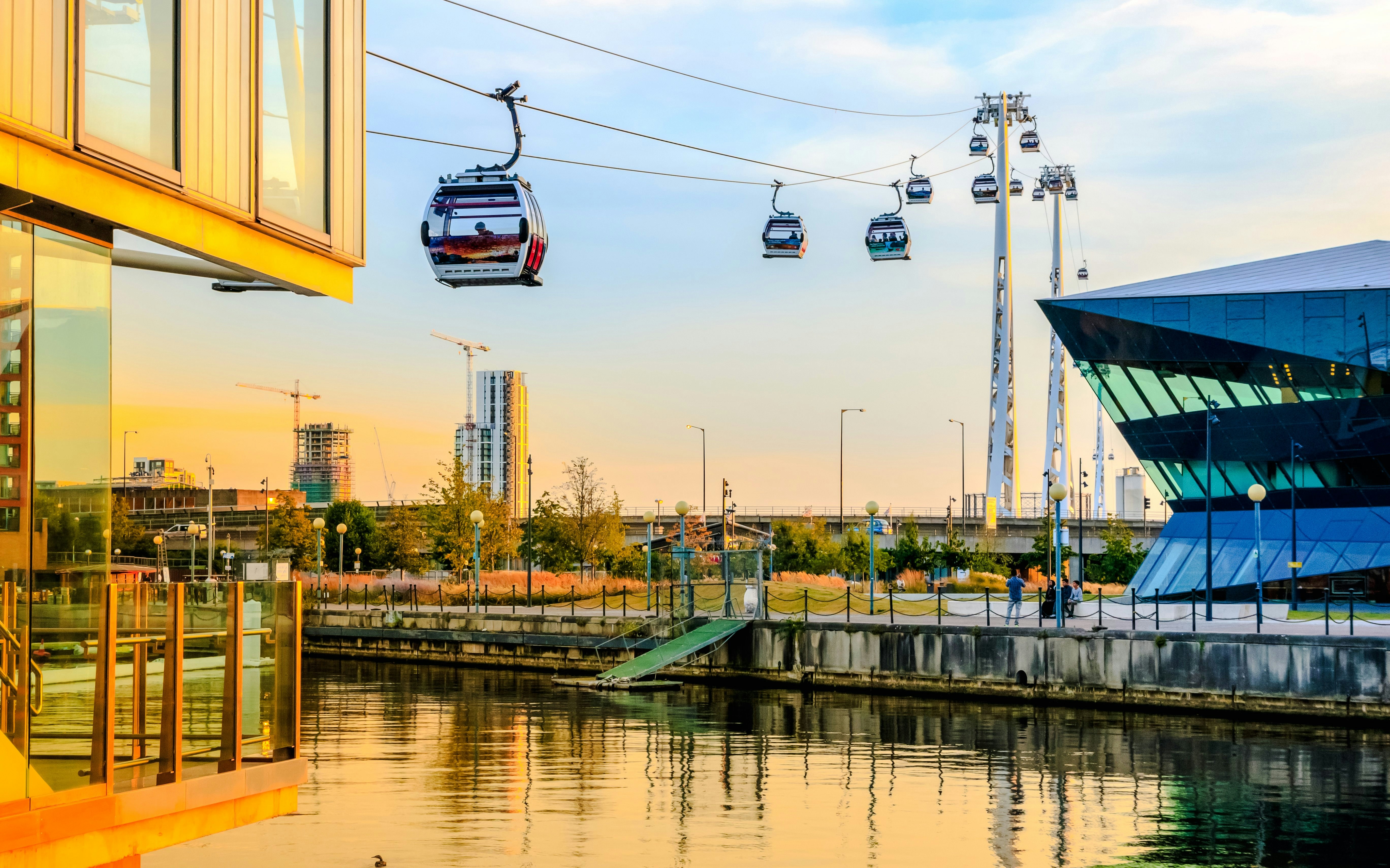 Cable cars over Royal Victoria Dock in London at sunset.