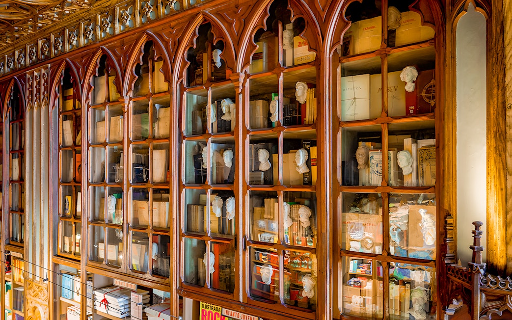 Lello Library interior with ornate wooden bookshelves and busts in Porto, Portugal.