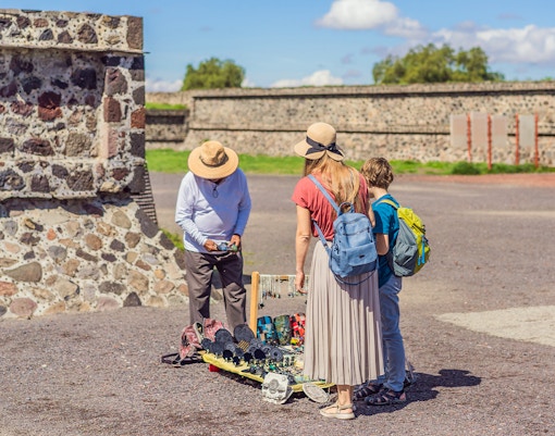 Mexican vendor selling crafts at Teotihuacan, Mexico with pyramids in the background.