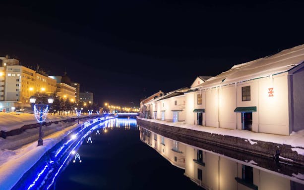 Otaru Canal at night with illuminated buildings and reflections on the water.