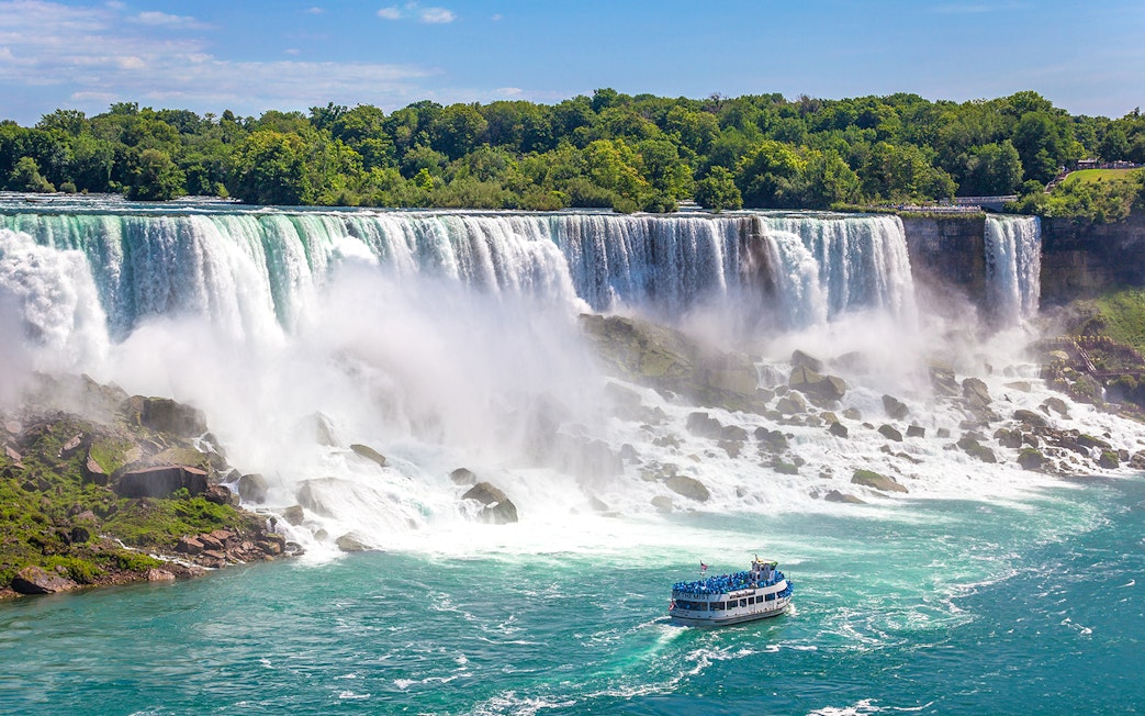 Boat approaching Niagara Falls with mist rising from the waterfall.