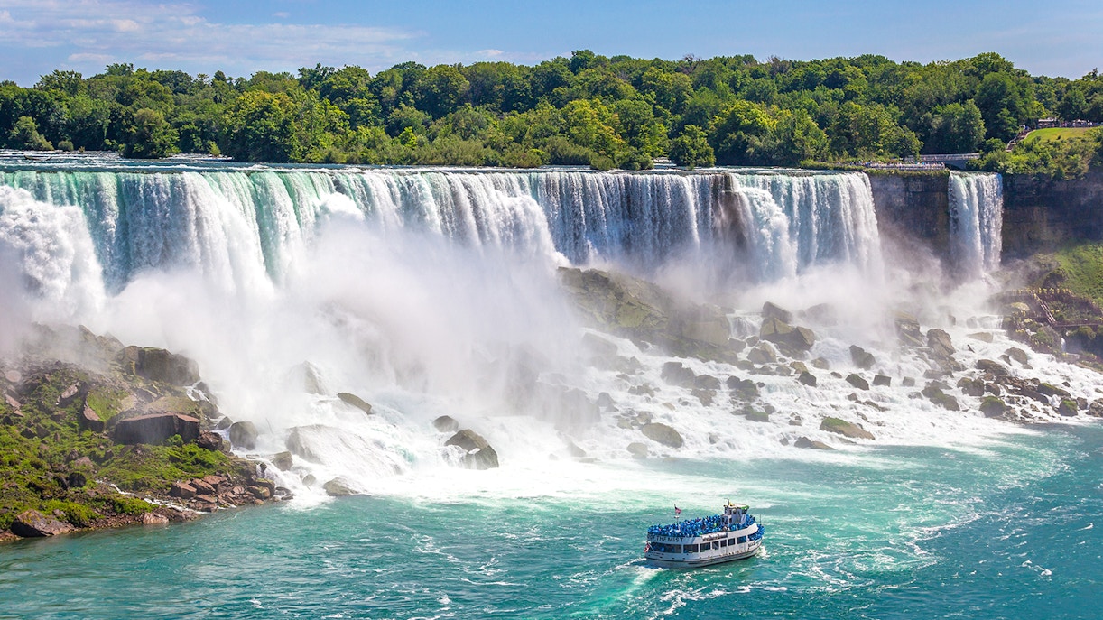 Maid of the Mist boat near Niagara Falls with tourists viewing the waterfall.