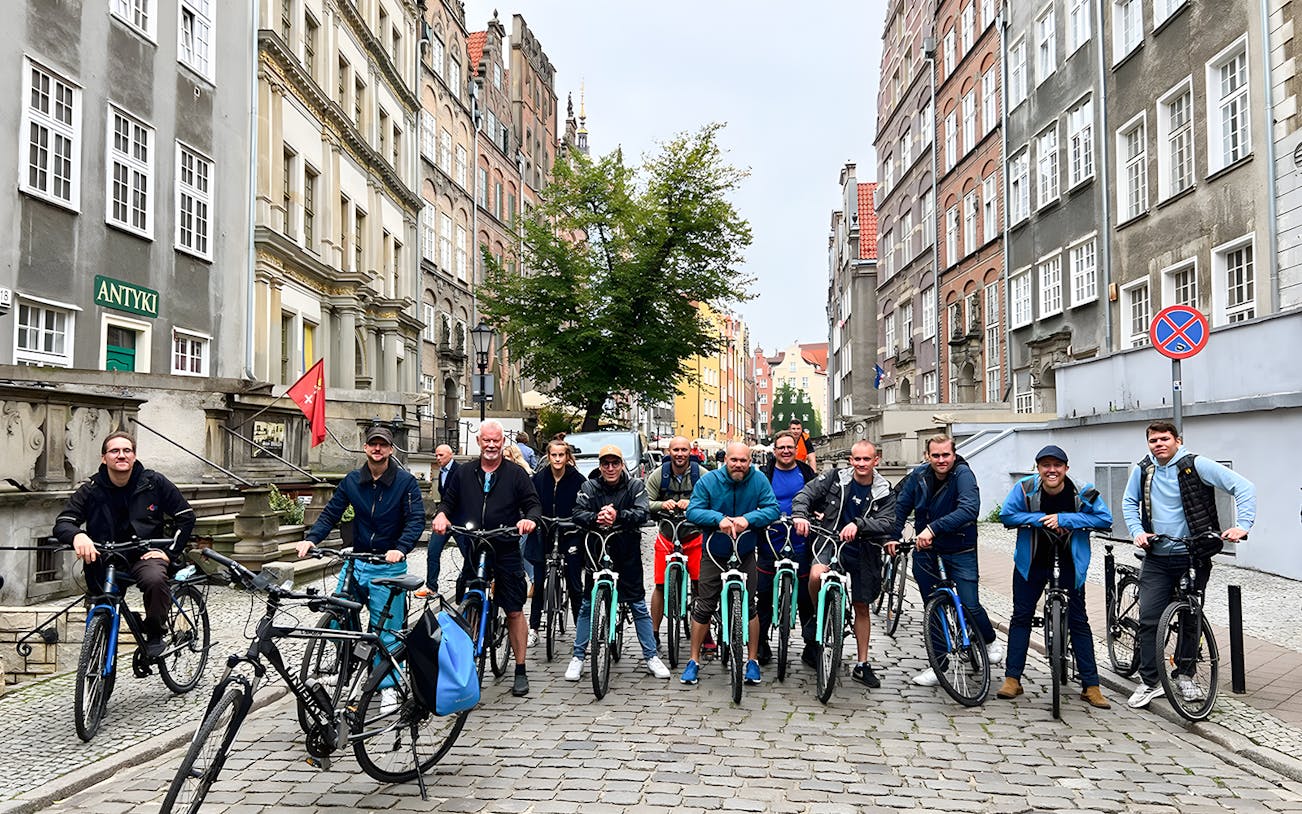 Group of cyclists on a cobblestone street during a Gdansk private bike tour.