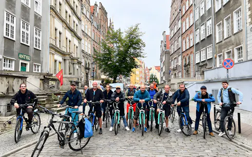 Group of cyclists on a cobblestone street during a Gdansk private bike tour.