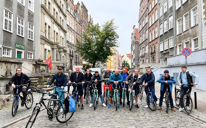 Group of cyclists on a cobblestone street during a Gdansk private bike tour.