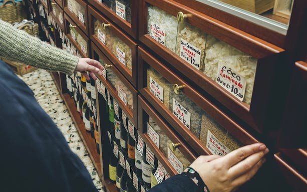 Hands selecting items from a shelf in a Porto food shop during a wine tour.