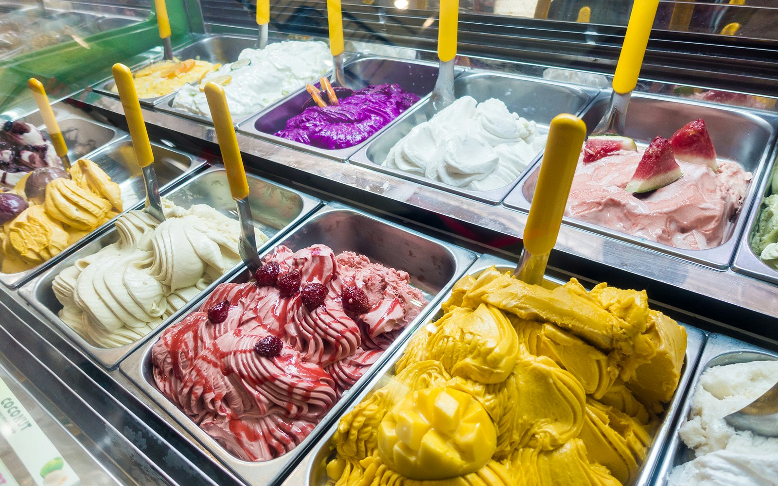 Assorted colorful gelato flavors in a display case.