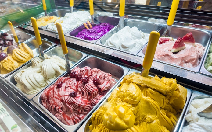Assorted colorful gelato flavors in a display case.