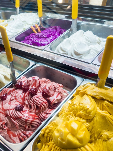 Assorted colorful gelato flavors in a display case.