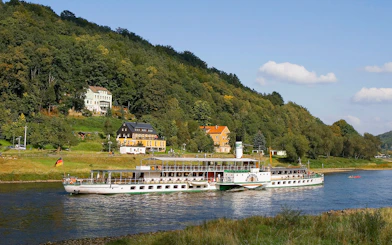 Elbe River cruise ship near Pillnitz Castle, Dresden, with hillside view.