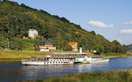 Elbe River cruise ship near Pillnitz Castle, Dresden, with hillside view.